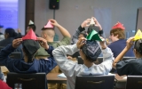 Students display their paper hat making abilities in a lesson that  highlights differences between economic systems.